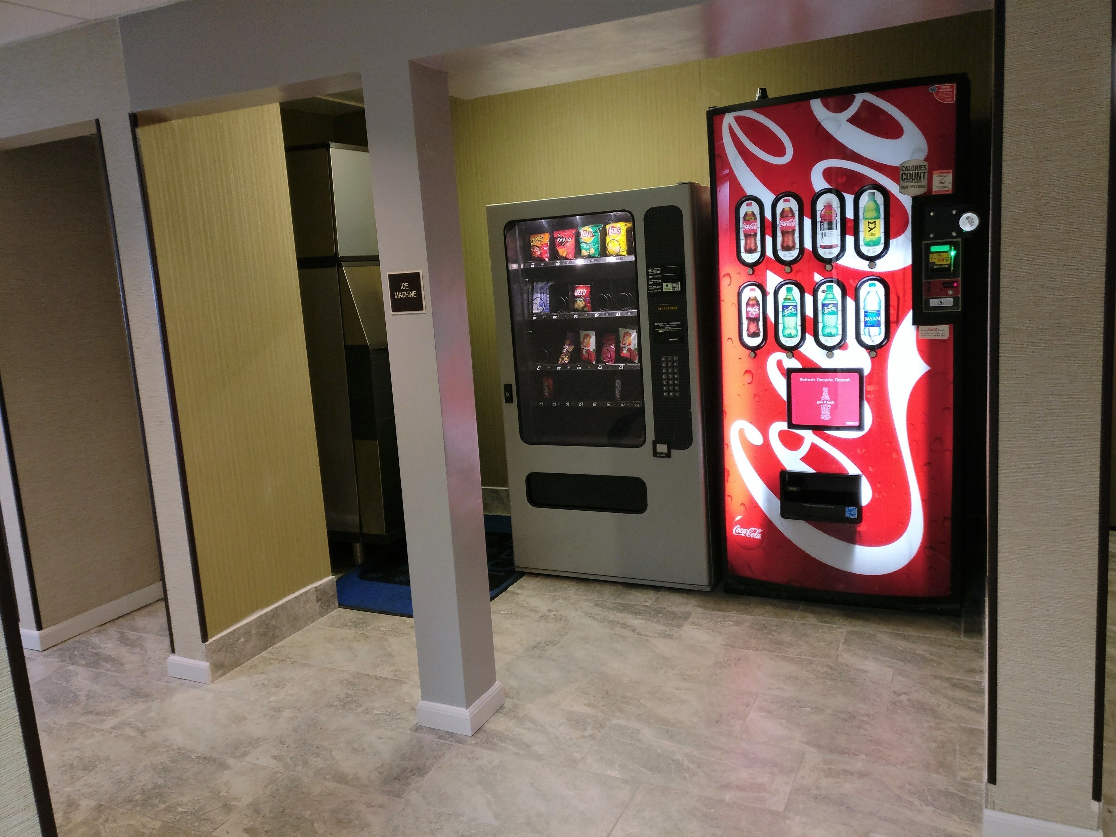 Una máquina expendedora con el logotipo de Coca-Cola y otra más pequeña de aperitivos.