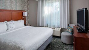 A hotel room with a large bed, a television, a desk, and a window with curtains. - Sonesta Select Boston Lowell Chelmsford  (Lowell)