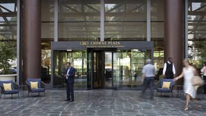 Der Eingang des Crowne Plaza Atlanta Perimeter at Ravinia mit Glastüren, Steinböden und Außenbestuhlung.
