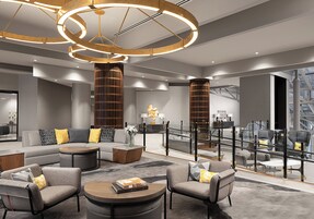 Ein modernes Interieur mit einem Ecksofa, einem runden Couchtisch und einer Glastrennwand.