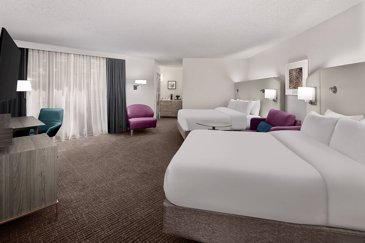 A hotel room with a large bed, a desk, a chair, and a small table.