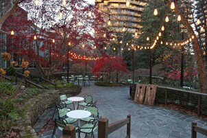 An outdoor patio area with stone flooring, green chairs, and tables.