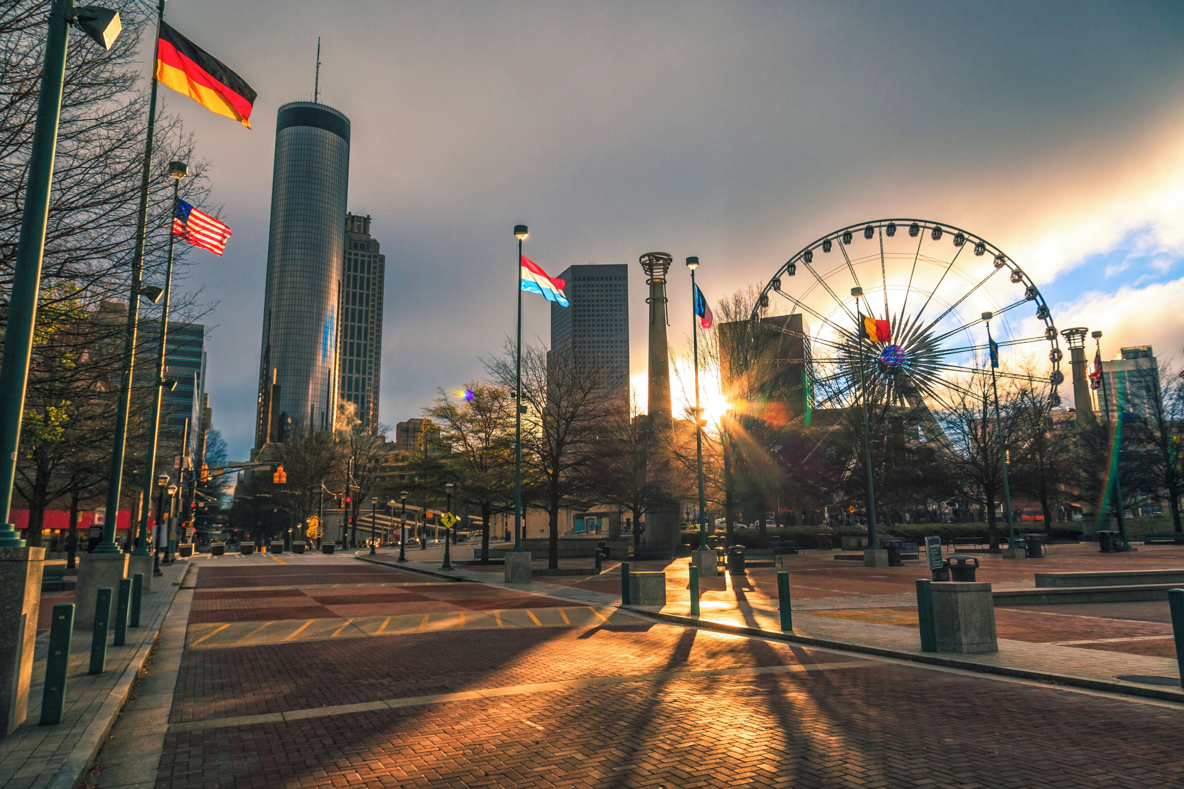 A city square with a Ferris wheel, flags, and modern buildings.