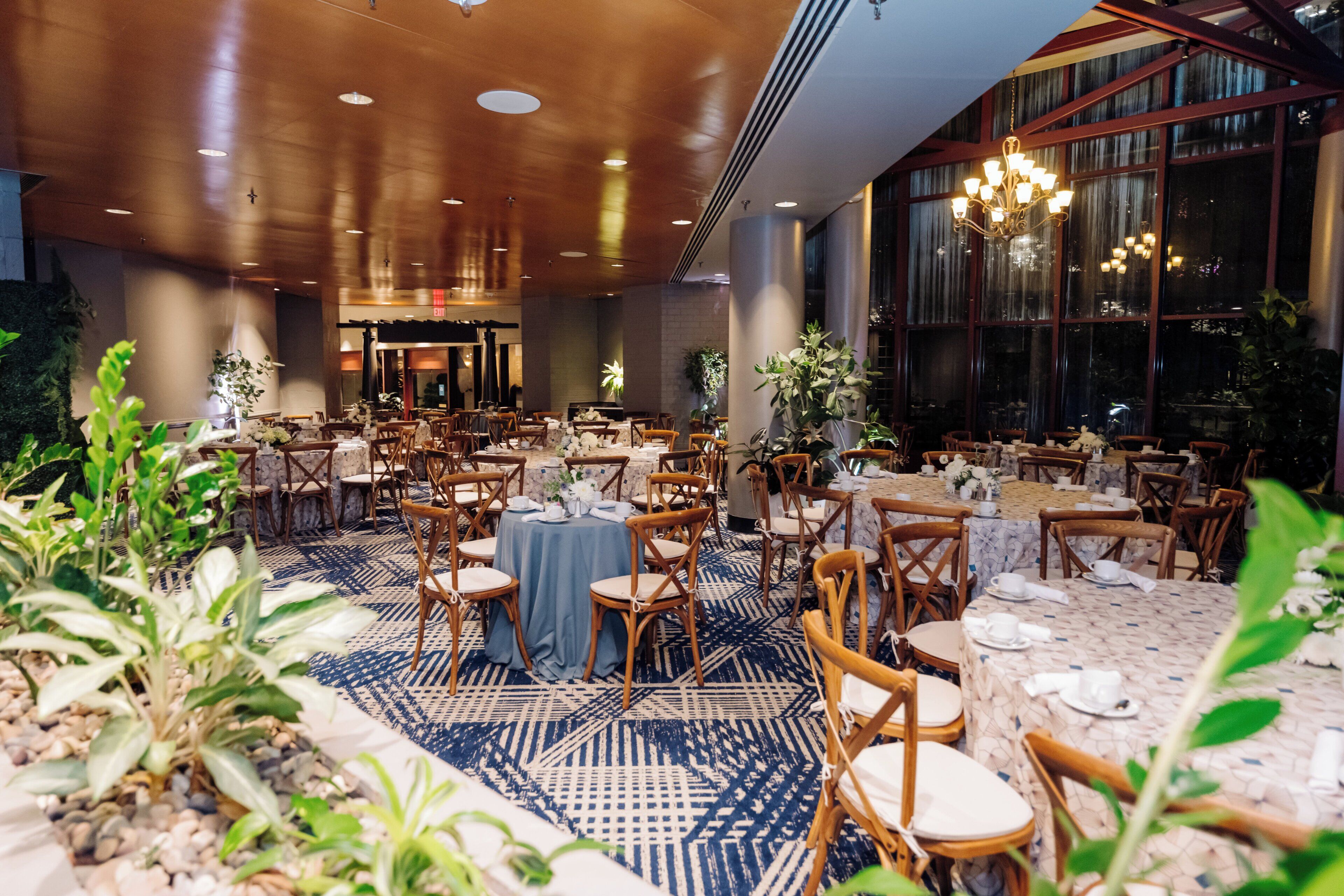 A spacious dining area with multiple tables and chairs, large windows, and a chandelier.