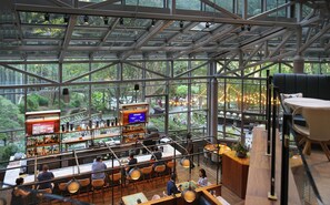 A modern bar with a high ceiling and large windows overlooking a lush garden. - Crowne Plaza Atlanta Perimeter at Ravinia by IHG (Atlanta)