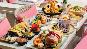 A dining table with a variety of dishes including tacos, seafood, and a burger. - Waldorf Towers South Beach (Miami Beach)