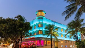 A multi-story hotel with a distinctive tower, a well-lit facade, and a visible restaurant area. - Waldorf Towers South Beach (Miami Beach)