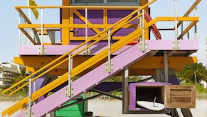 A lifeguard tower with purple and yellow colors, stairs, and a flag. - Waldorf Towers South Beach (Miami Beach)
