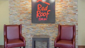 Una habitación con dos sillones de cuero, una mesita y una pared con el letrero de 'Red Roof Inn'.