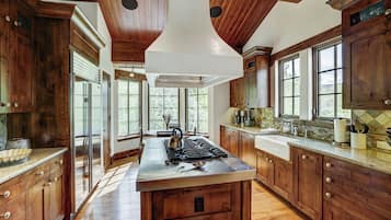 A spacious kitchen with wooden cabinets, a central island, stainless steel appliances, and large windows allowing natural light.