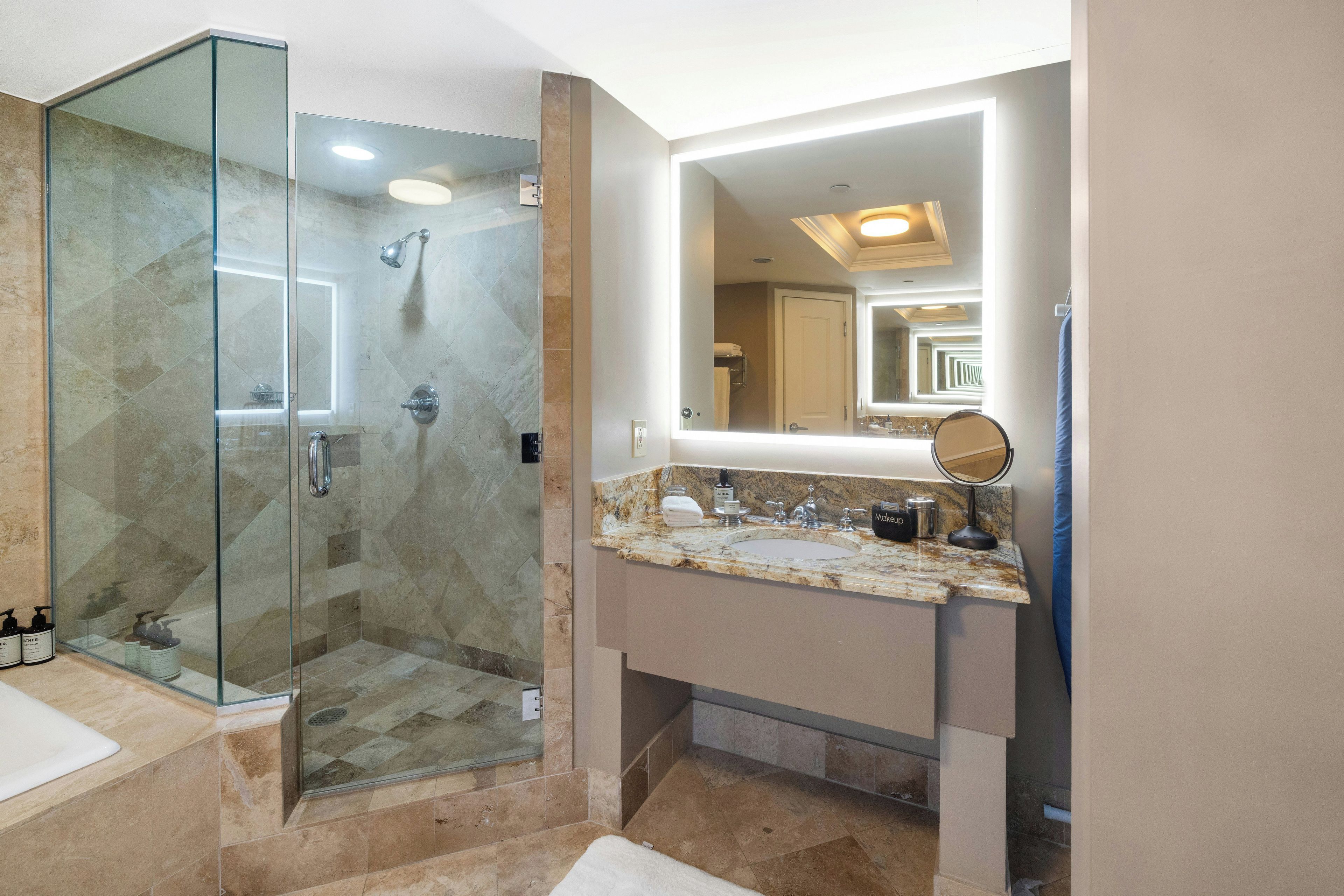 A bathroom with a glass-enclosed shower, a vanity with a sink, and a mirror.
