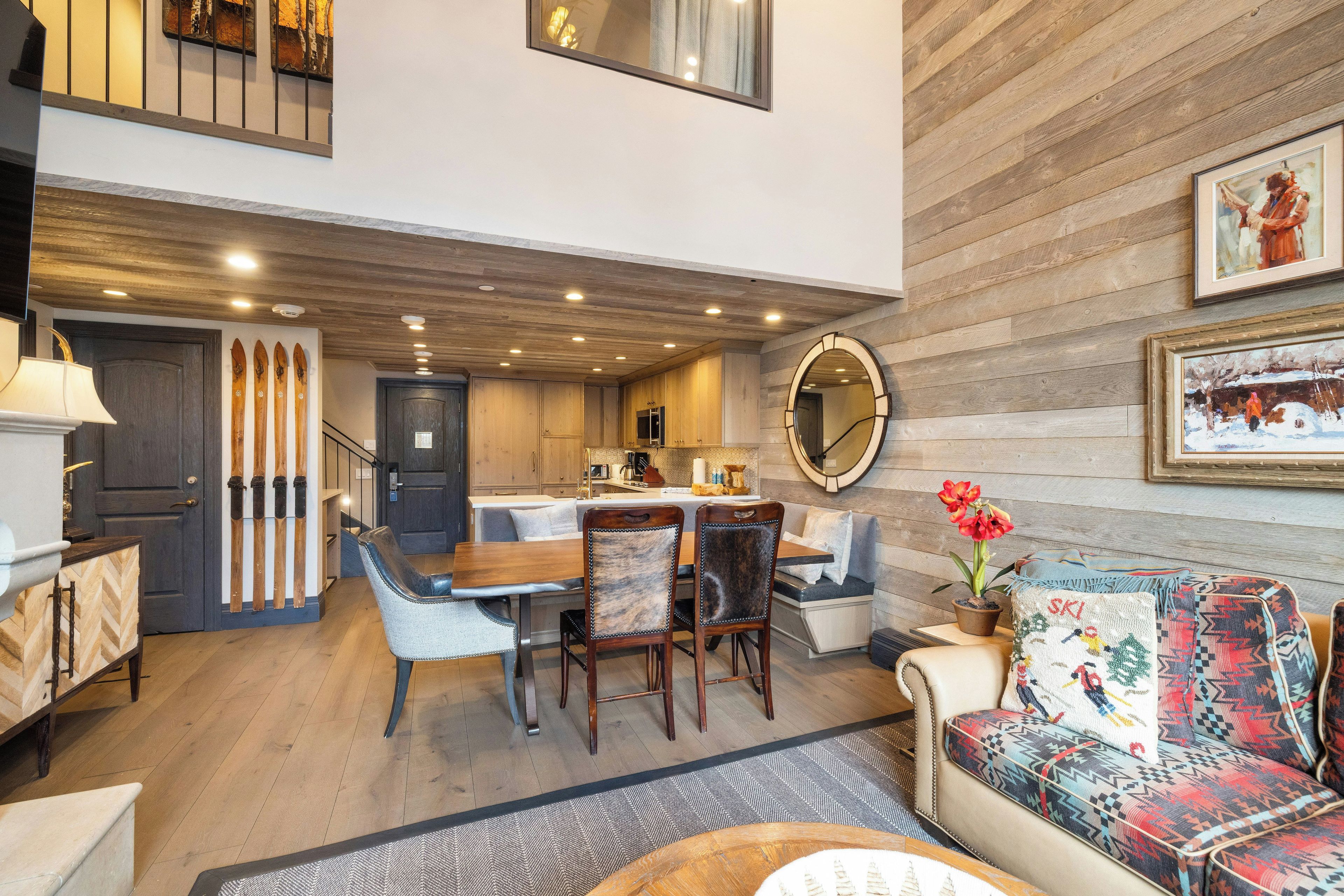 Un espacio habitable amplio con techo de madera, una mesa de comedor con sillas, un sofá y un espejo grande en la pared.