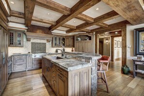 A spacious kitchen with wooden beams, granite countertops, and a large island.