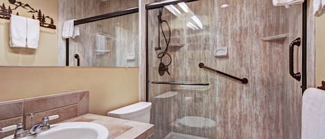 A modern bathroom with a glass-enclosed shower, a sink, and a toilet.