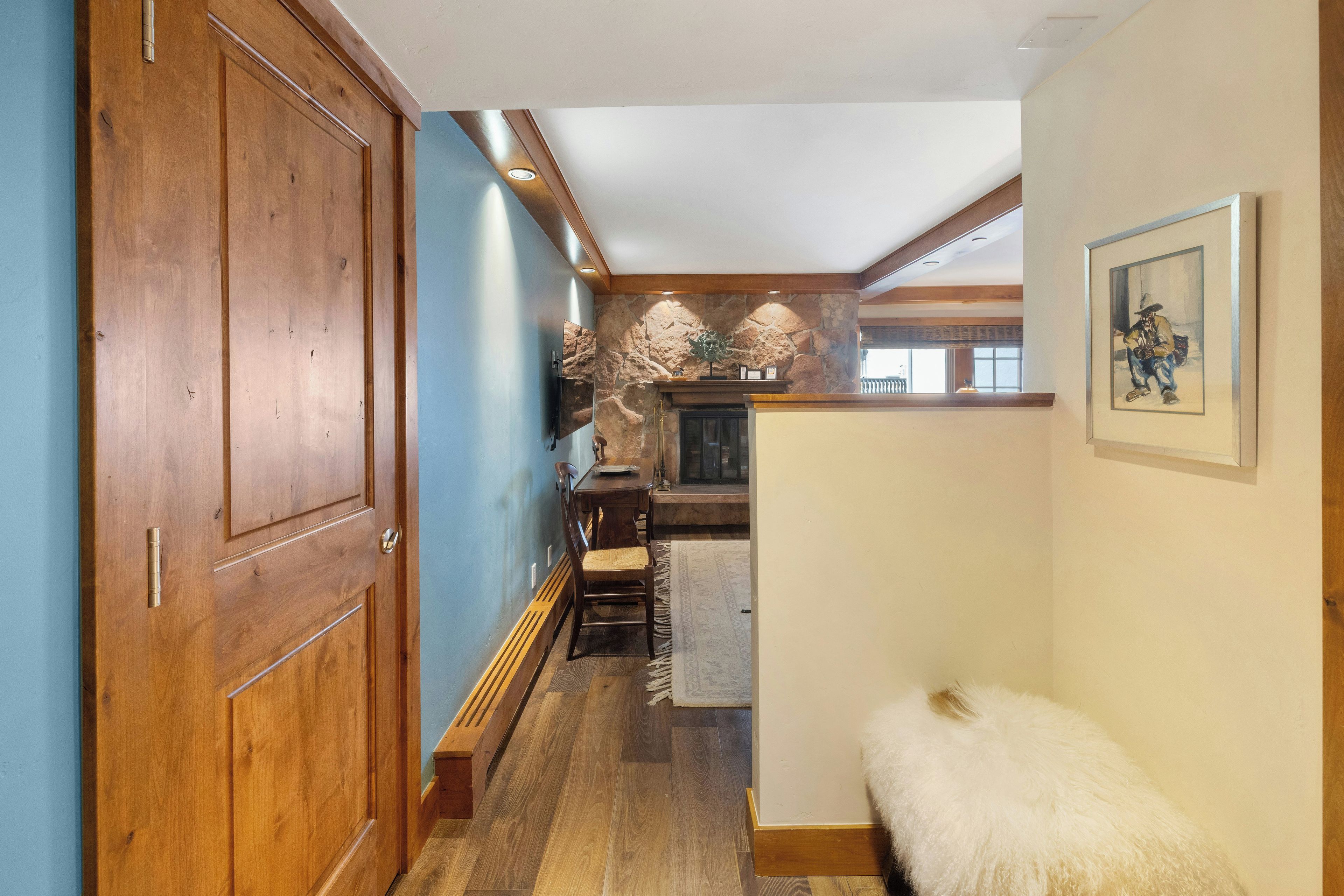 A hallway with wooden doors, a stone wall, a fireplace, and a framed picture on the wall.