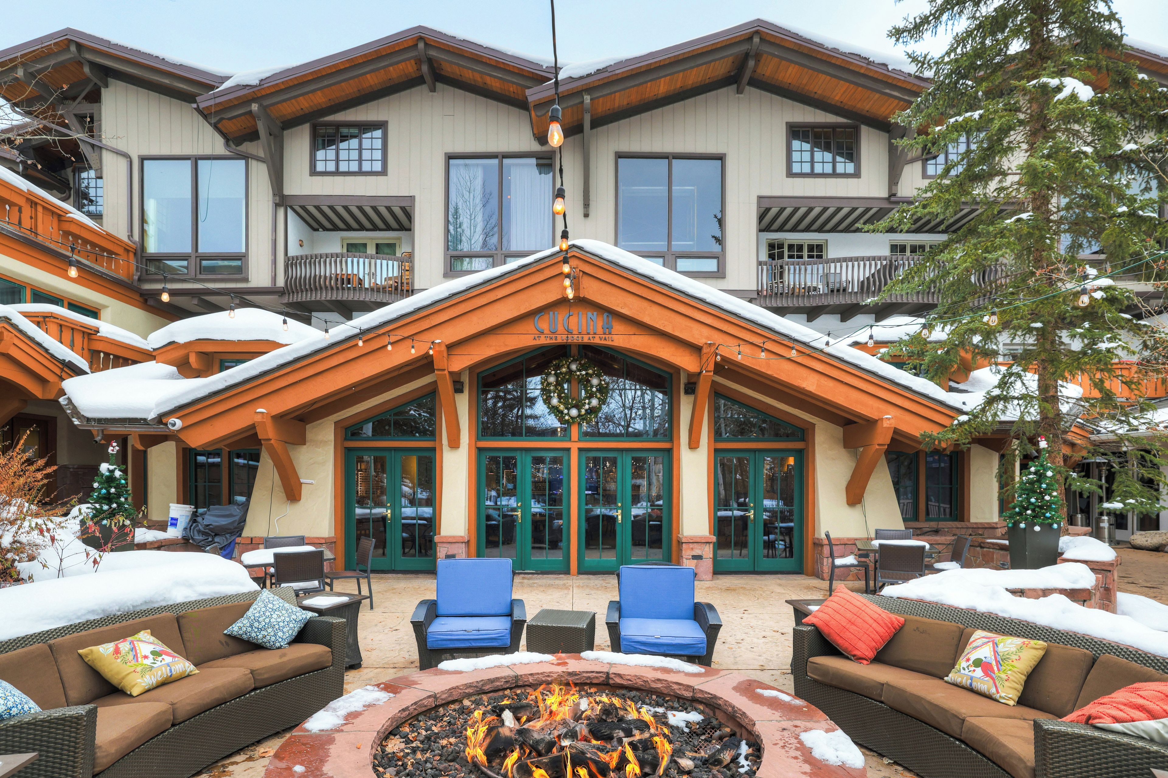 A lodge with a fire pit, outdoor seating, and a large entrance.