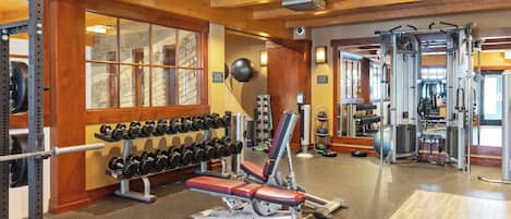 A gym with weightlifting equipment, dumbbells, and exercise machines.