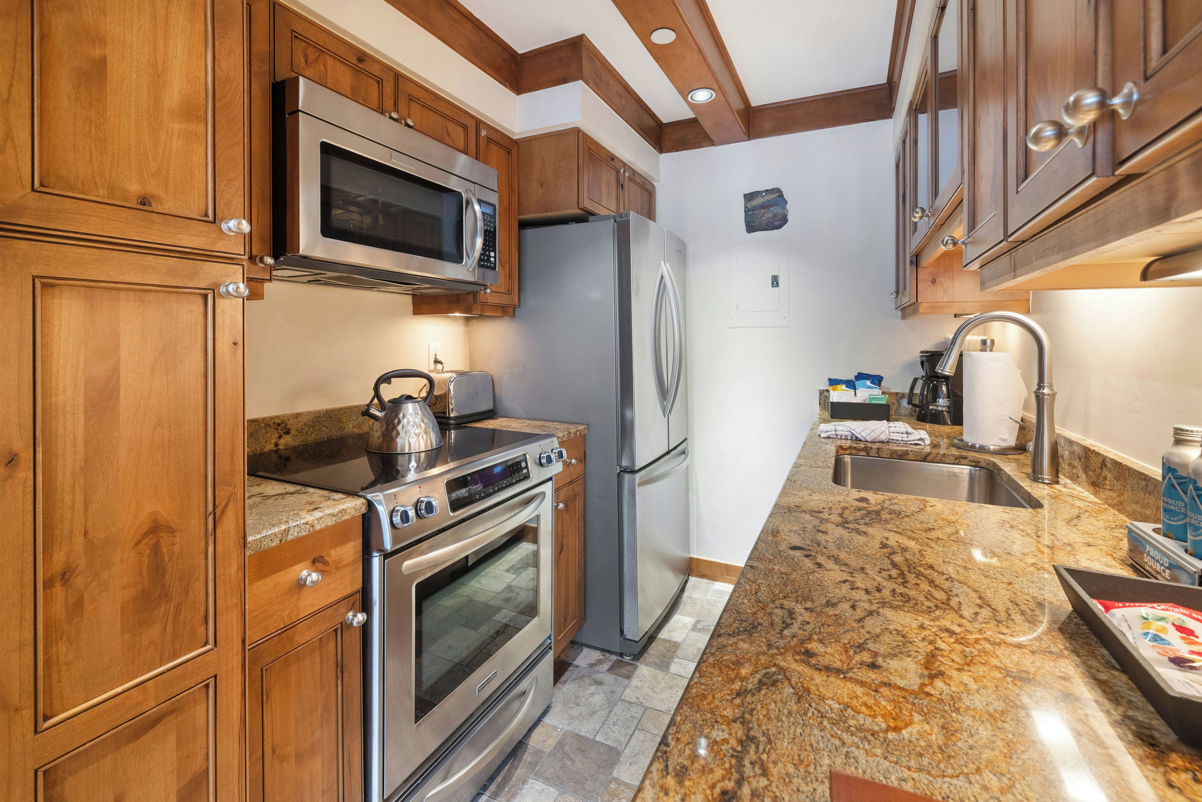 Una cocina con armarios de madera, electrodomésticos de acero inoxidable, encimeras de granito y un microondas integrado.