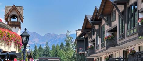A traditional chalet-style building with wooden balconies and flower boxes, set against a backdrop of mountains.