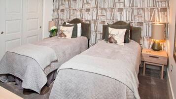 A bedroom with two beds, a bookshelf, a nightstand, and a door.