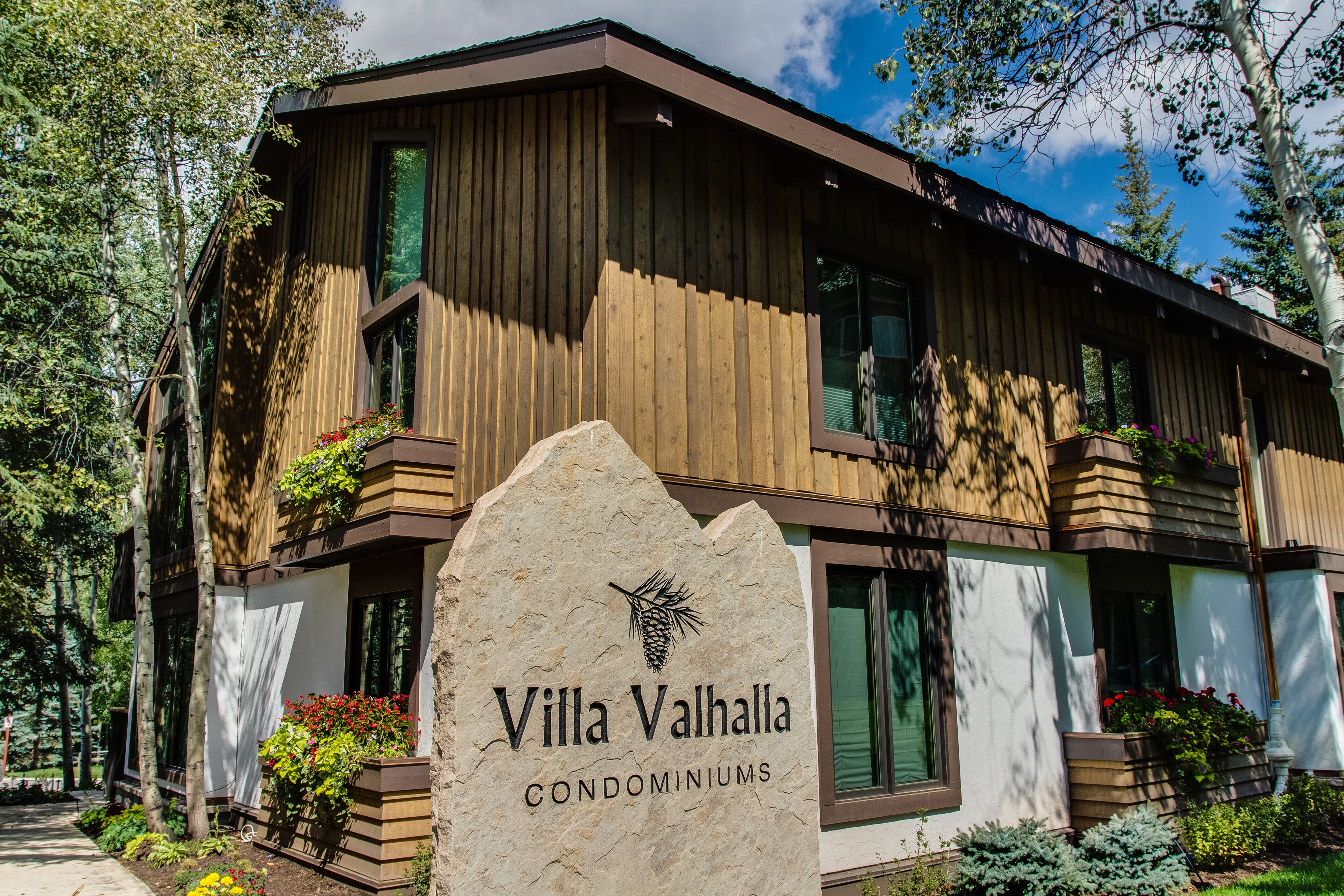 A wooden building with balconies and a stone sign that reads "Villa Valhalla Condominiums".