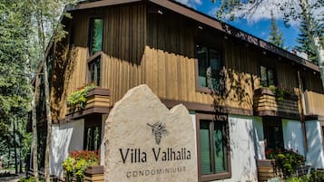 A wooden building with balconies and a stone sign that reads "Villa Valhalla Condominiums".