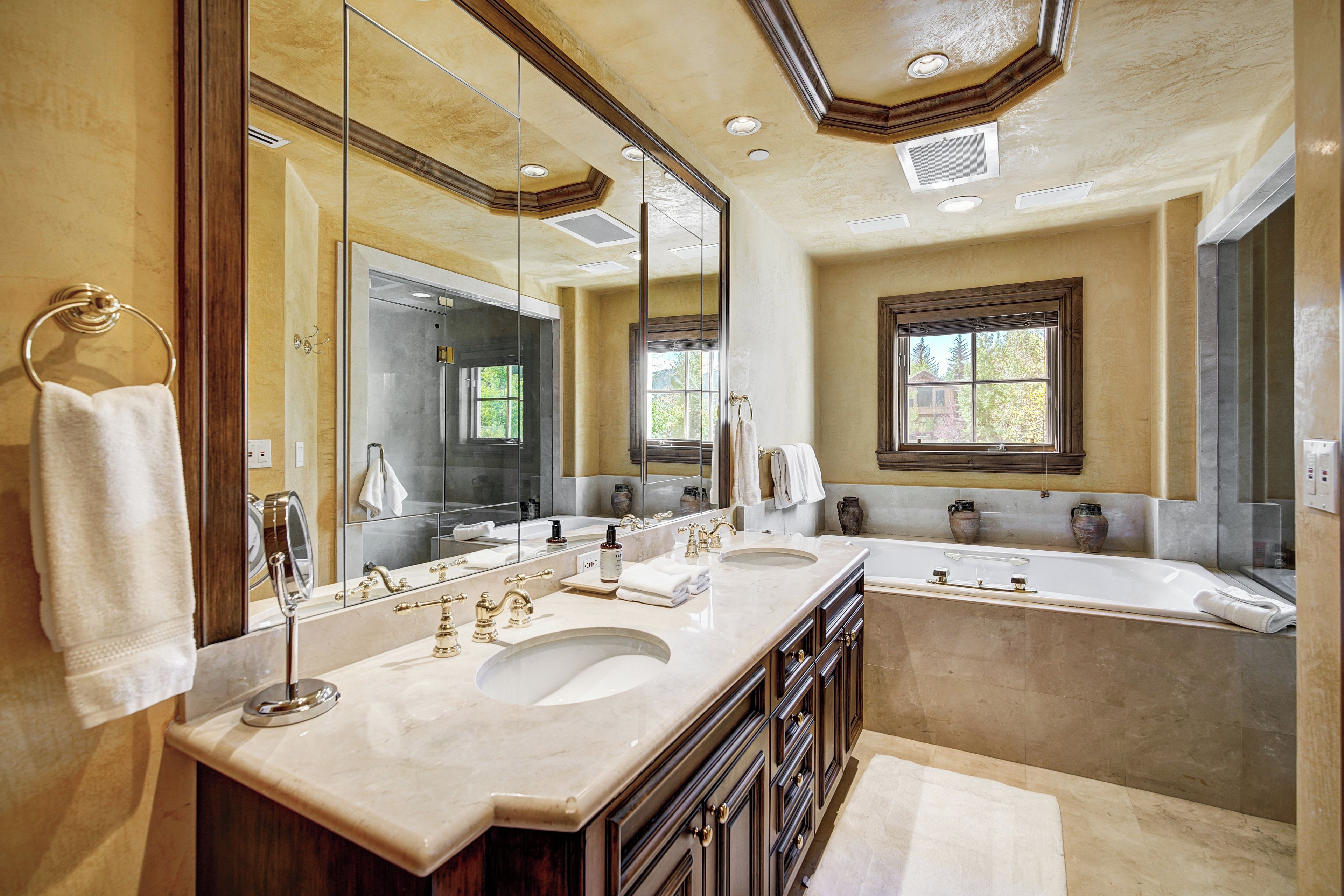 A spacious bathroom with two sinks, a large mirror, and a bathtub.