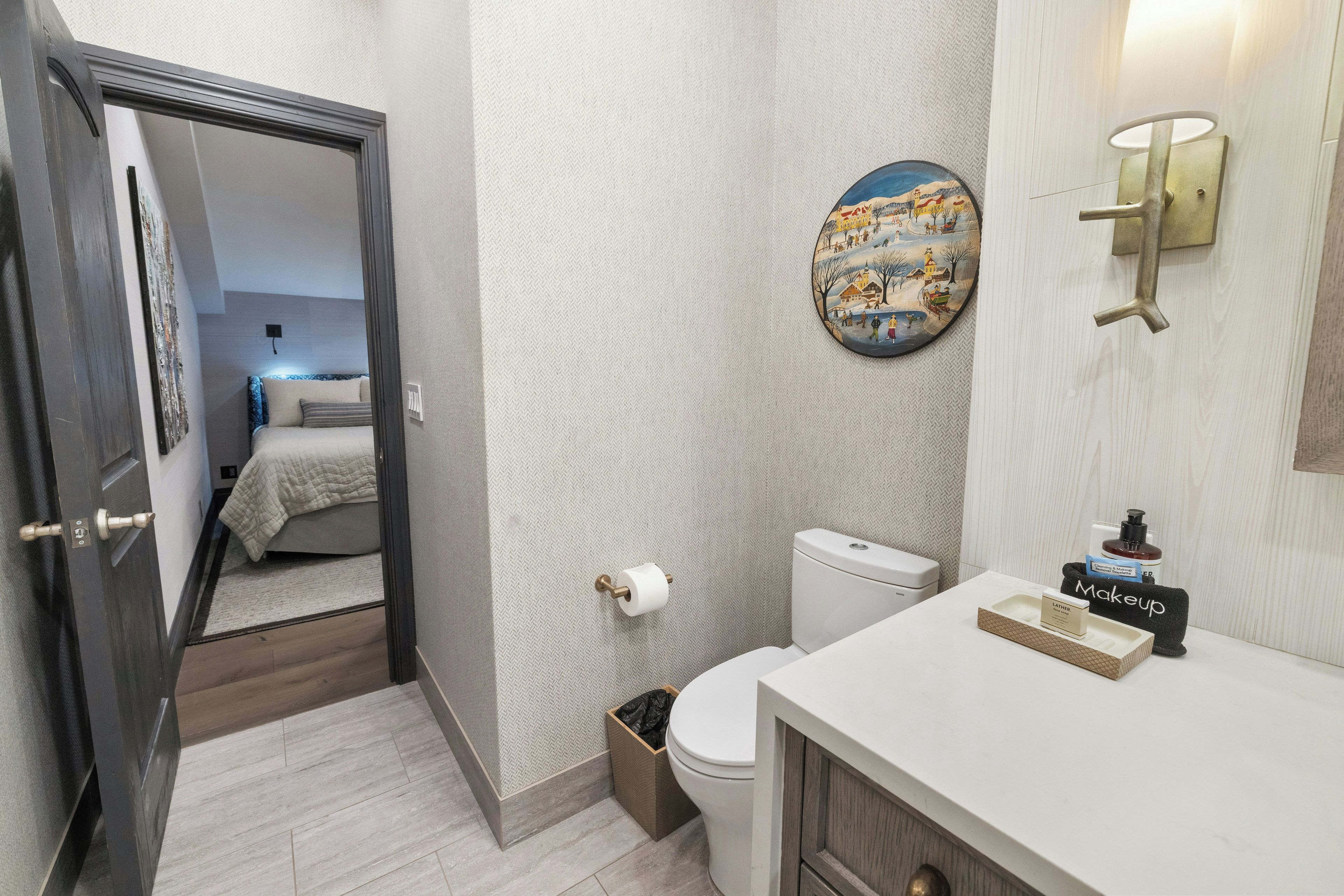 Een badkamer met toilet, wastafel en spiegel met een wandlamp.
