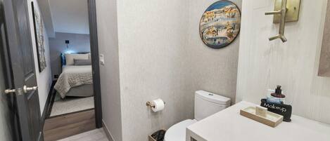 Een badkamer met toilet, wastafel en spiegel met een wandlamp.
