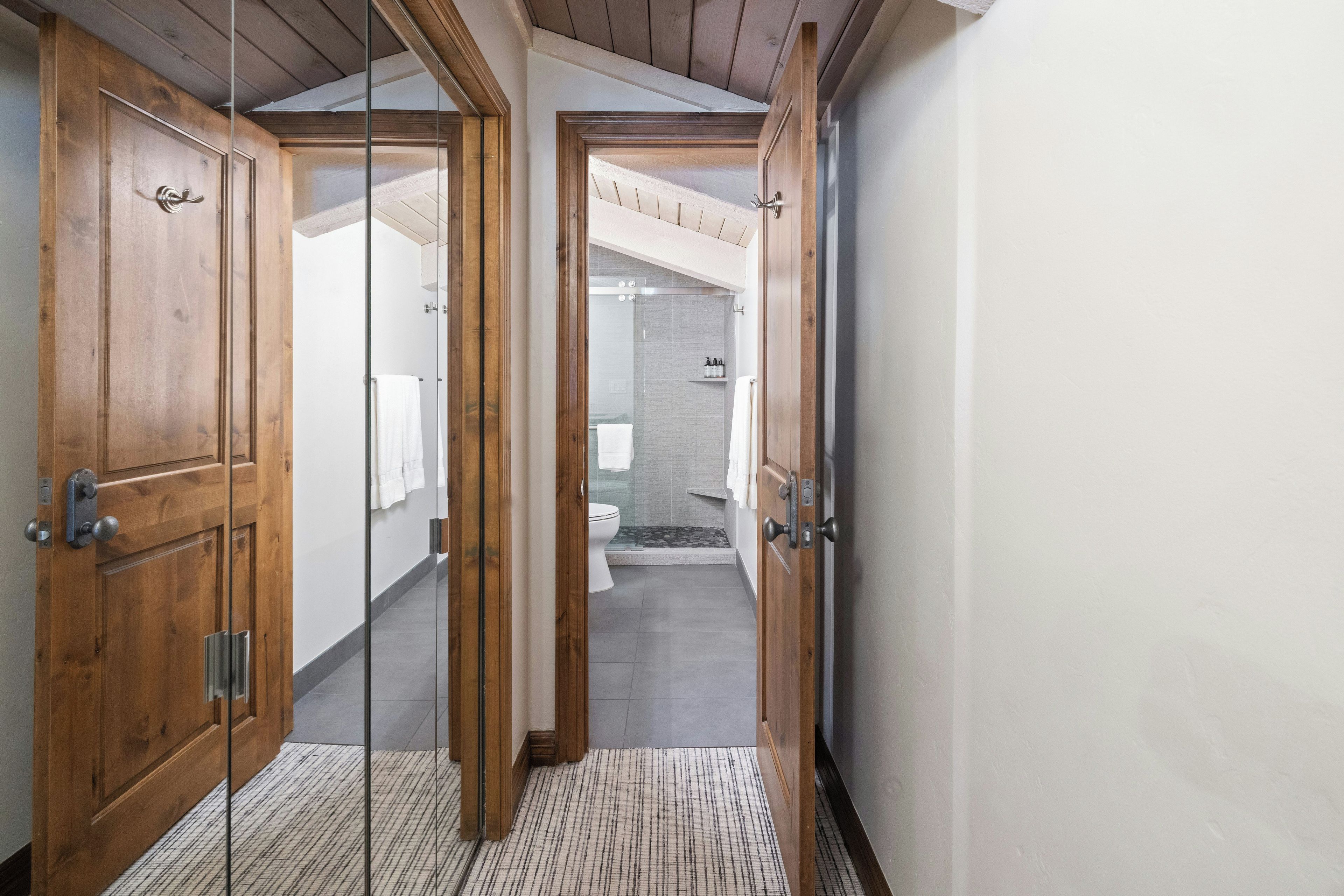 A hallway leading to a bathroom with a shower, toilet, and a towel rack.