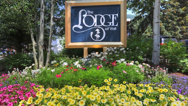 A sign for 'The Lodge at Vail' surrounded by a garden with various flowers. - The Lodge at Vail, a RockResort by Vail Resorts (Vail)