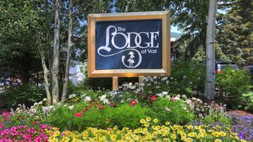 A sign for 'The Lodge at Vail' surrounded by a garden with various flowers.