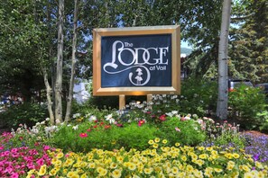 A sign for 'The Lodge at Vail' surrounded by a garden with various flowers.