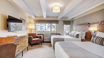 Habitación de hotel con cama, escritorio, silla, televisión y ventana con vistas a edificios.