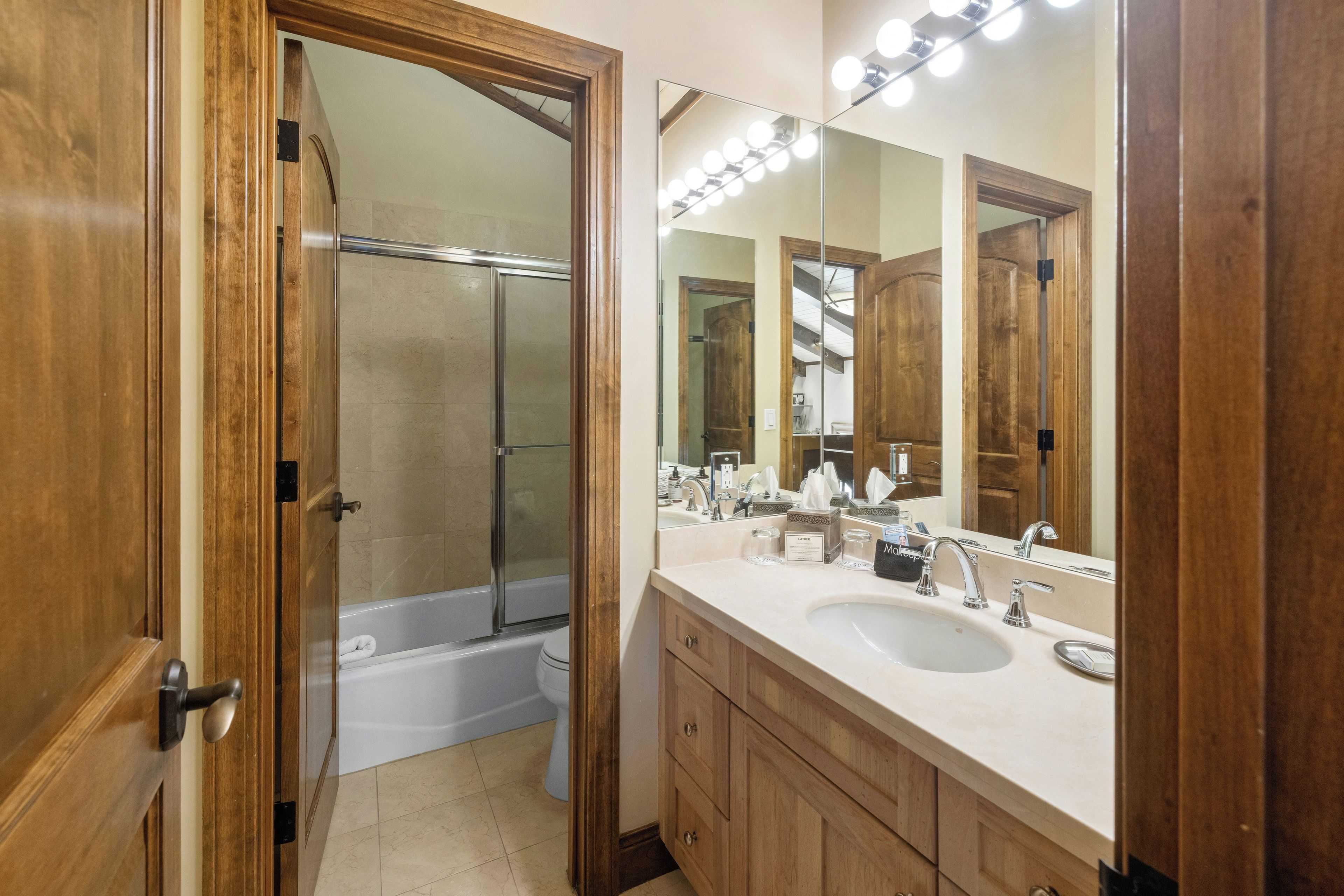 Un baño con ducha, bañera, tocador con un espejo grande y lavabo.