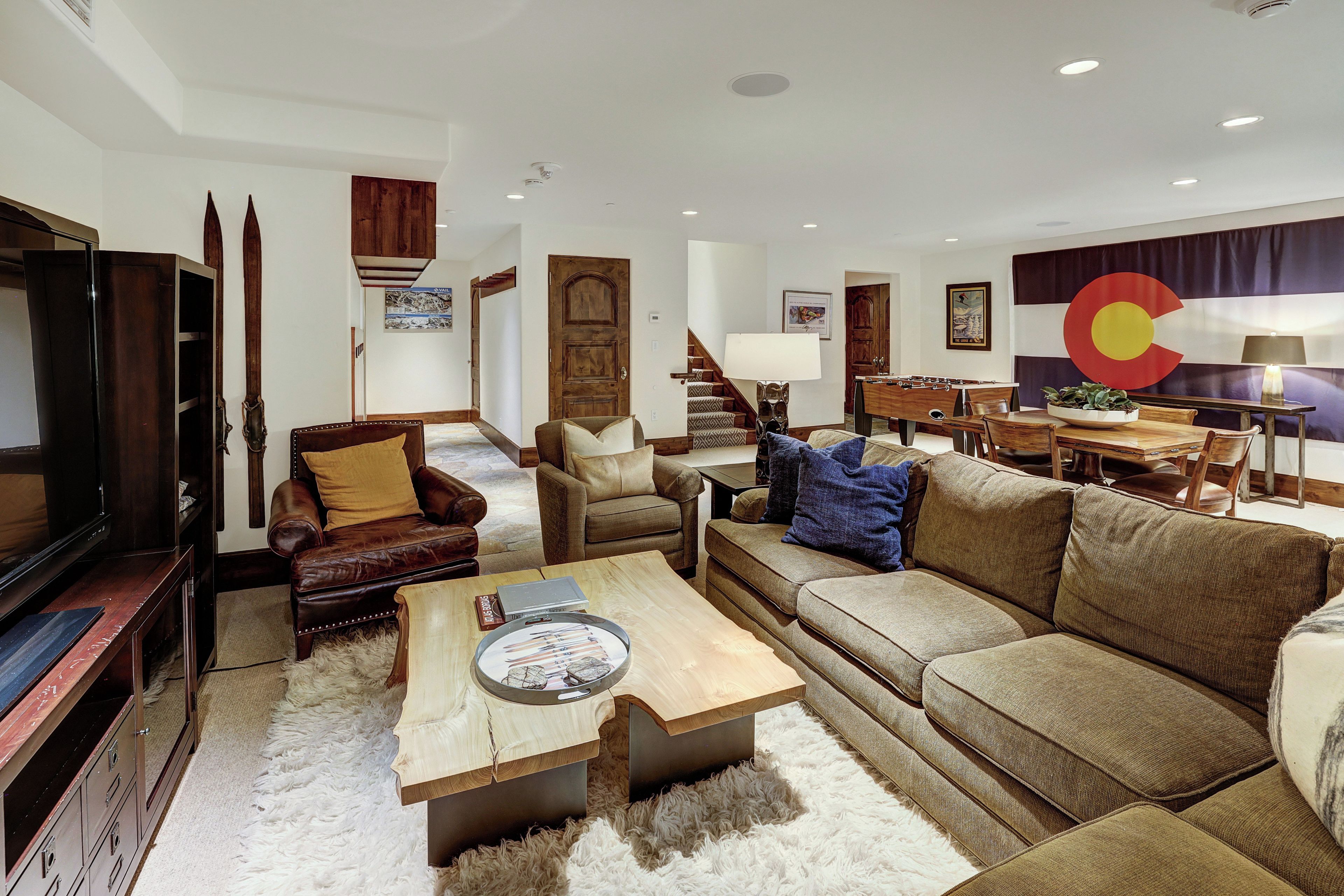 Una sala de estar con sofá, sillones, una mesa de centro y televisor.