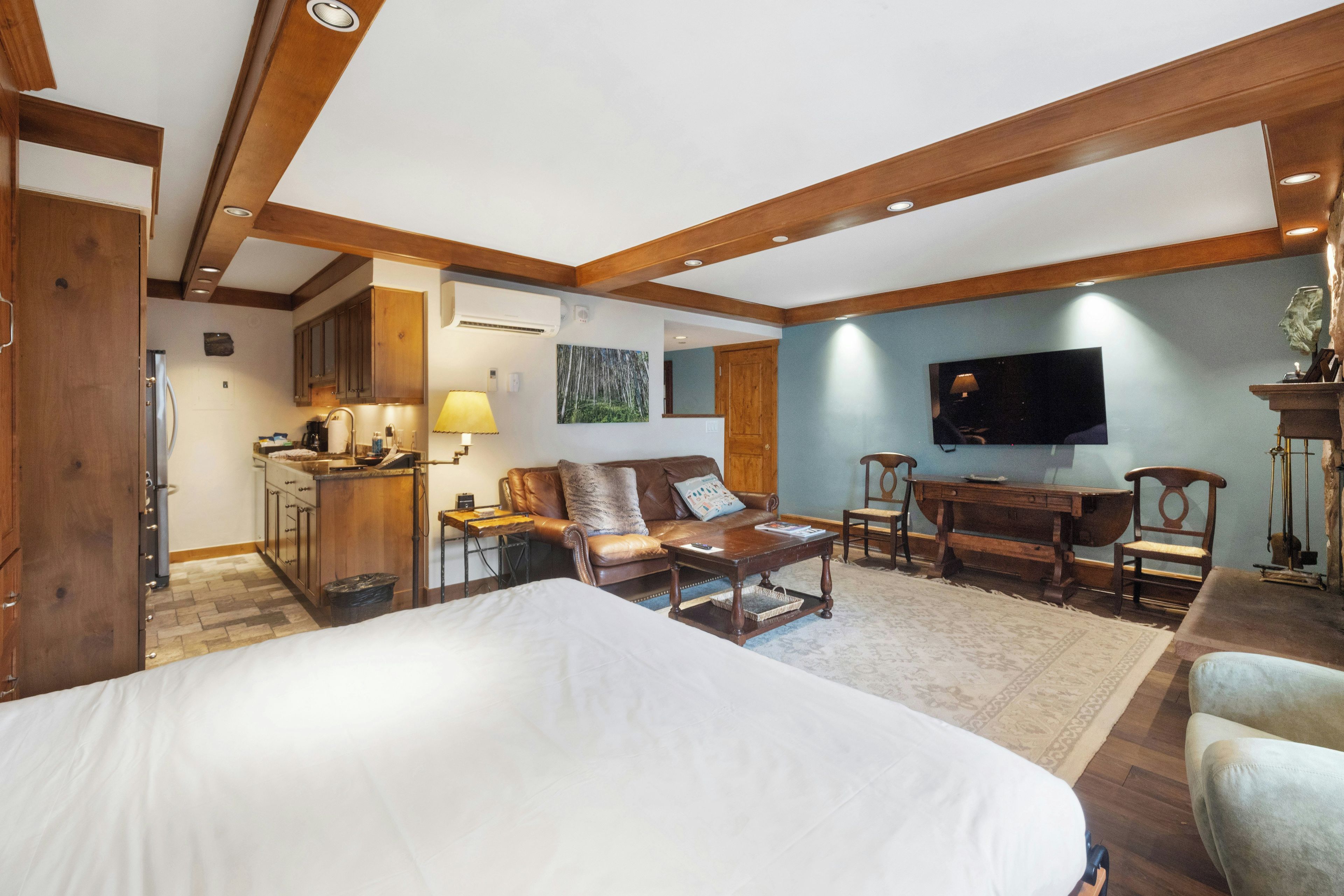 A hotel room with a large bed, a sitting area with a sofa and chairs, a television, and a kitchenette.