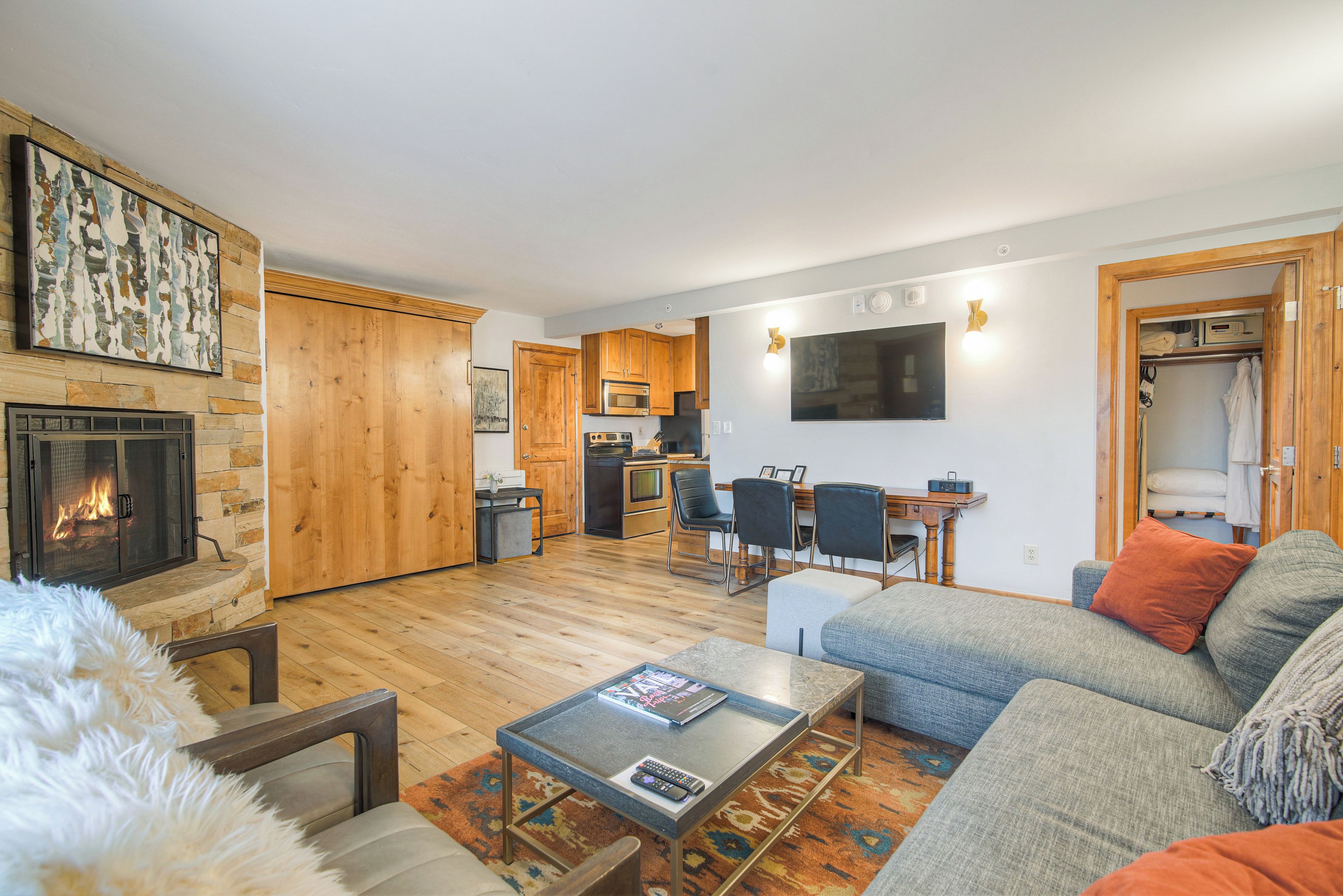 A modern living room with a fireplace, a dining area, and a kitchen.