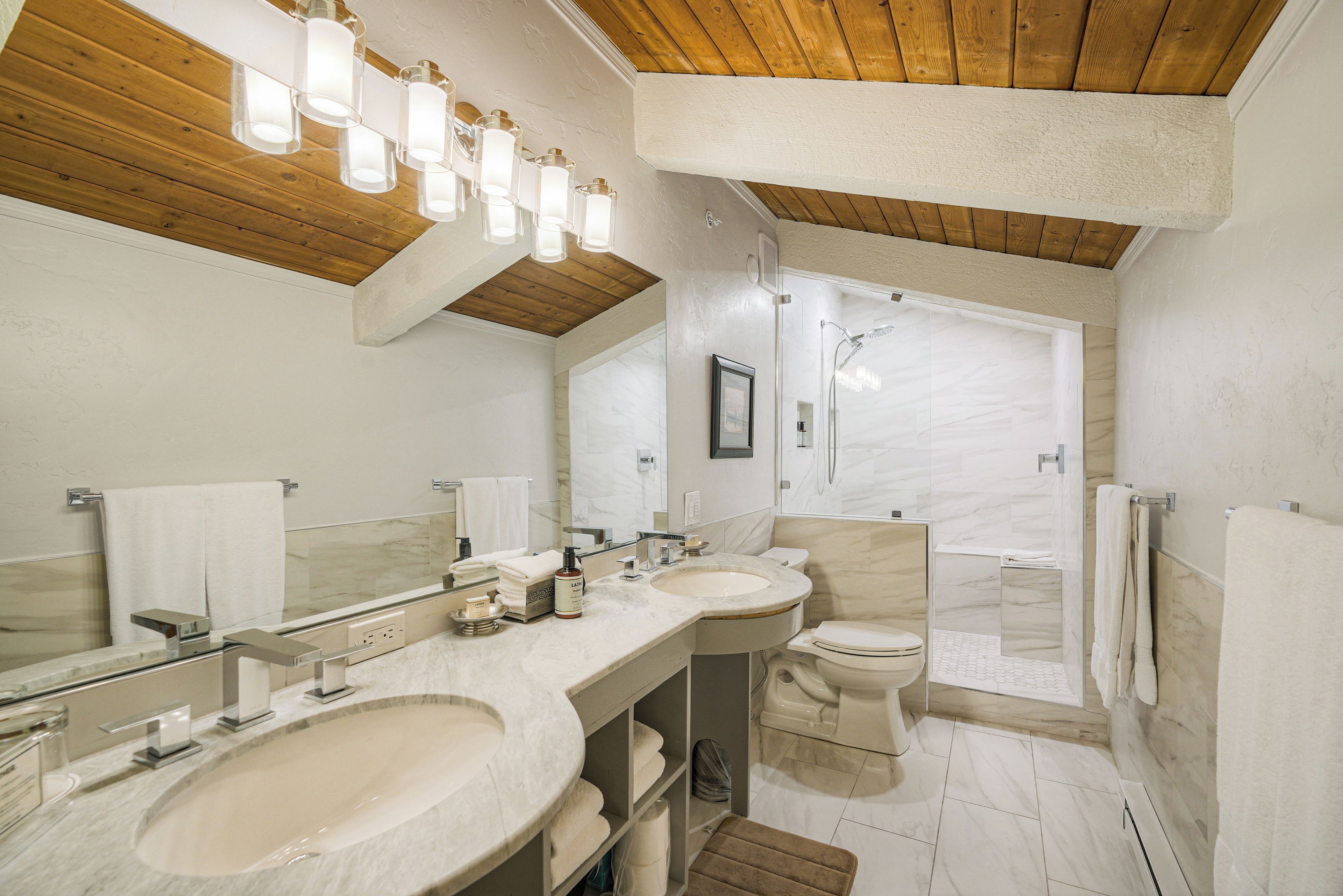 A modern bathroom with two sinks, a toilet, and a shower.