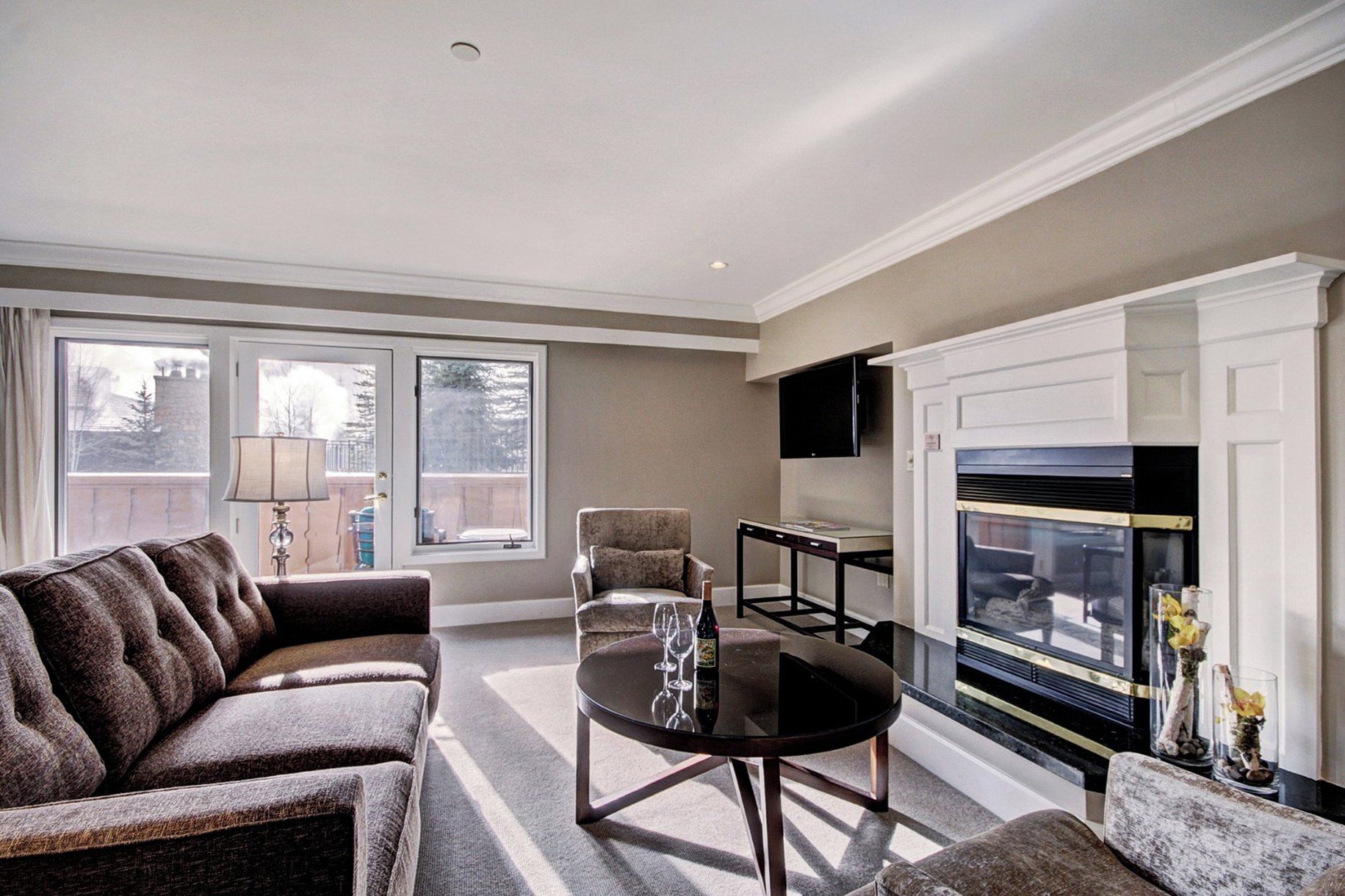 A living room with a sofa, a glass table, a fireplace, and a television.