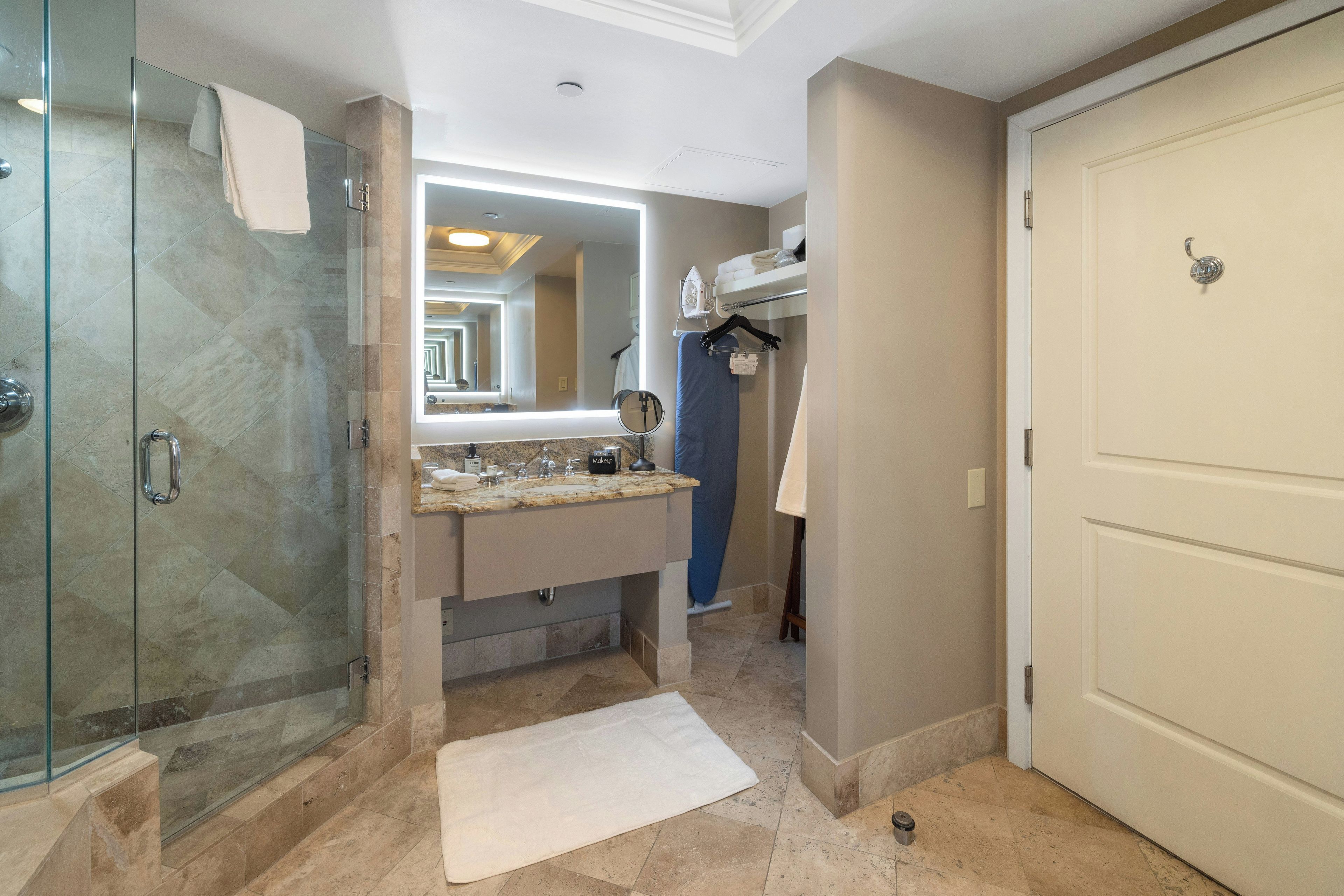 A modern bathroom with a glass shower enclosure, a vanity with a mirror, and a walk-in closet.