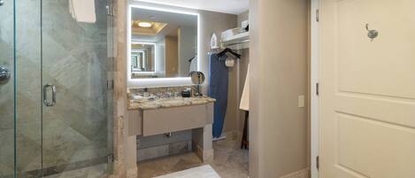 A modern bathroom with a glass shower enclosure, a vanity with a mirror, and a walk-in closet.