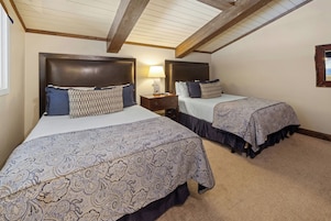 Una habitación con dos camas, cada una con cabecera y mesita de noche.