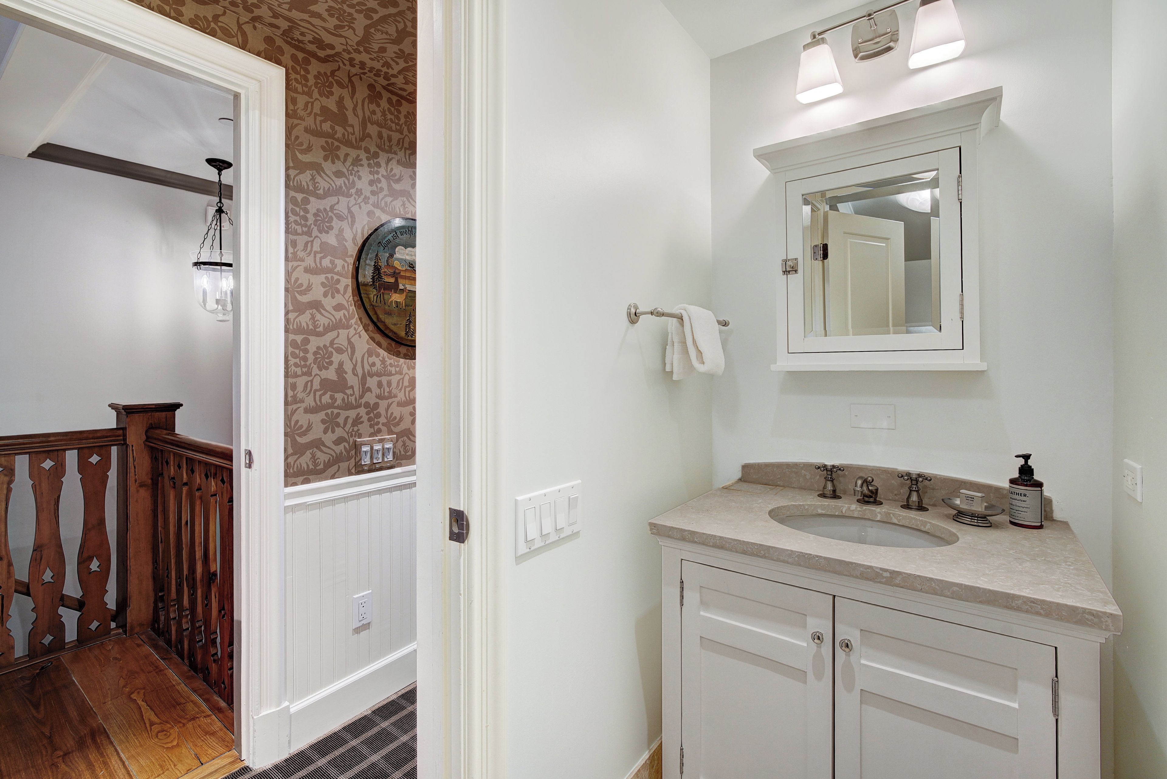 A bathroom with a sink, mirror, and towel rack.