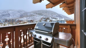 A balcony with a grill, wooden railings, and a view of snow-covered mountains. - The Lodge at Vail, a RockResort by Vail Resorts (Vail)