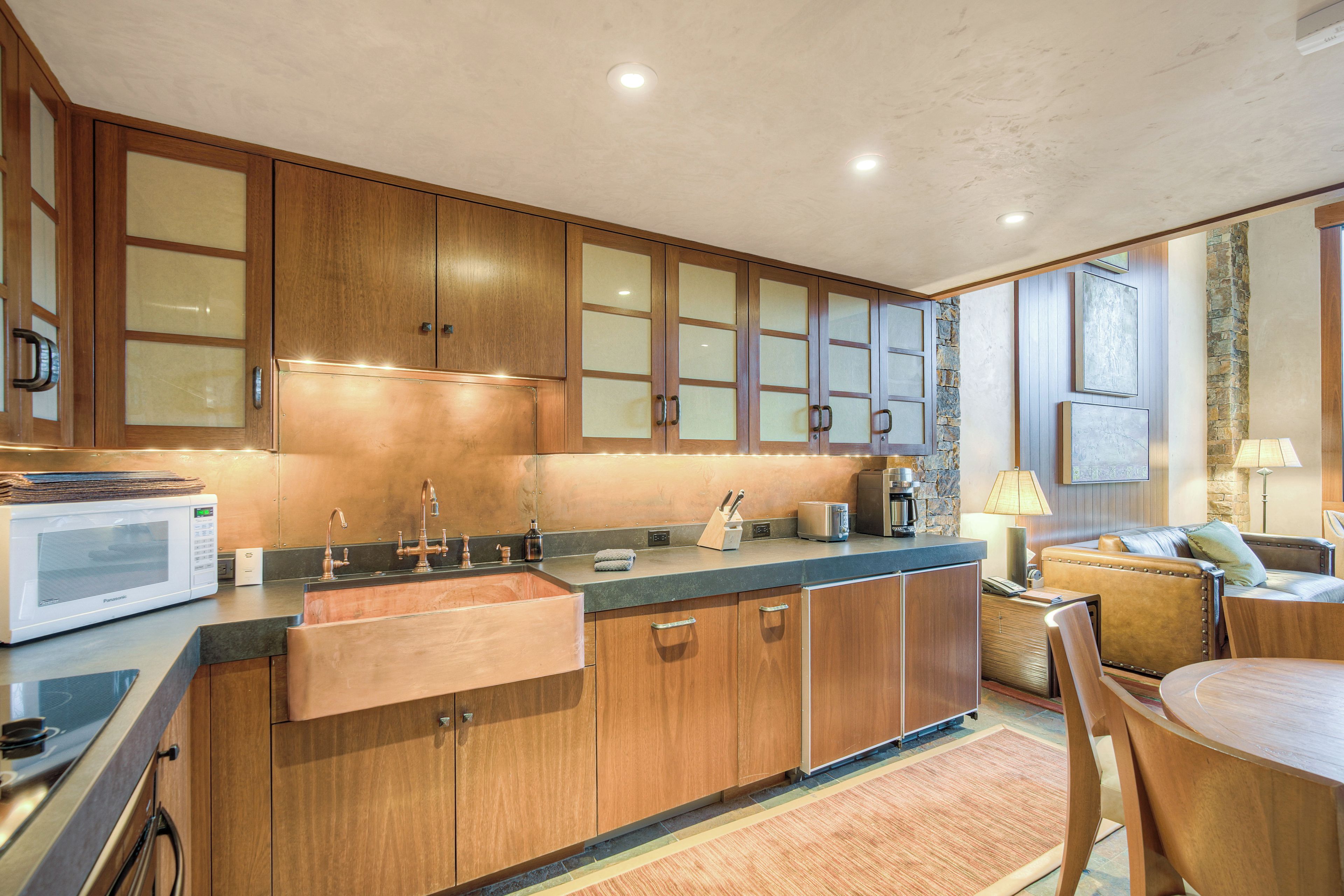 A modern kitchen with wooden cabinets, a built-in microwave, and a coffee maker.
