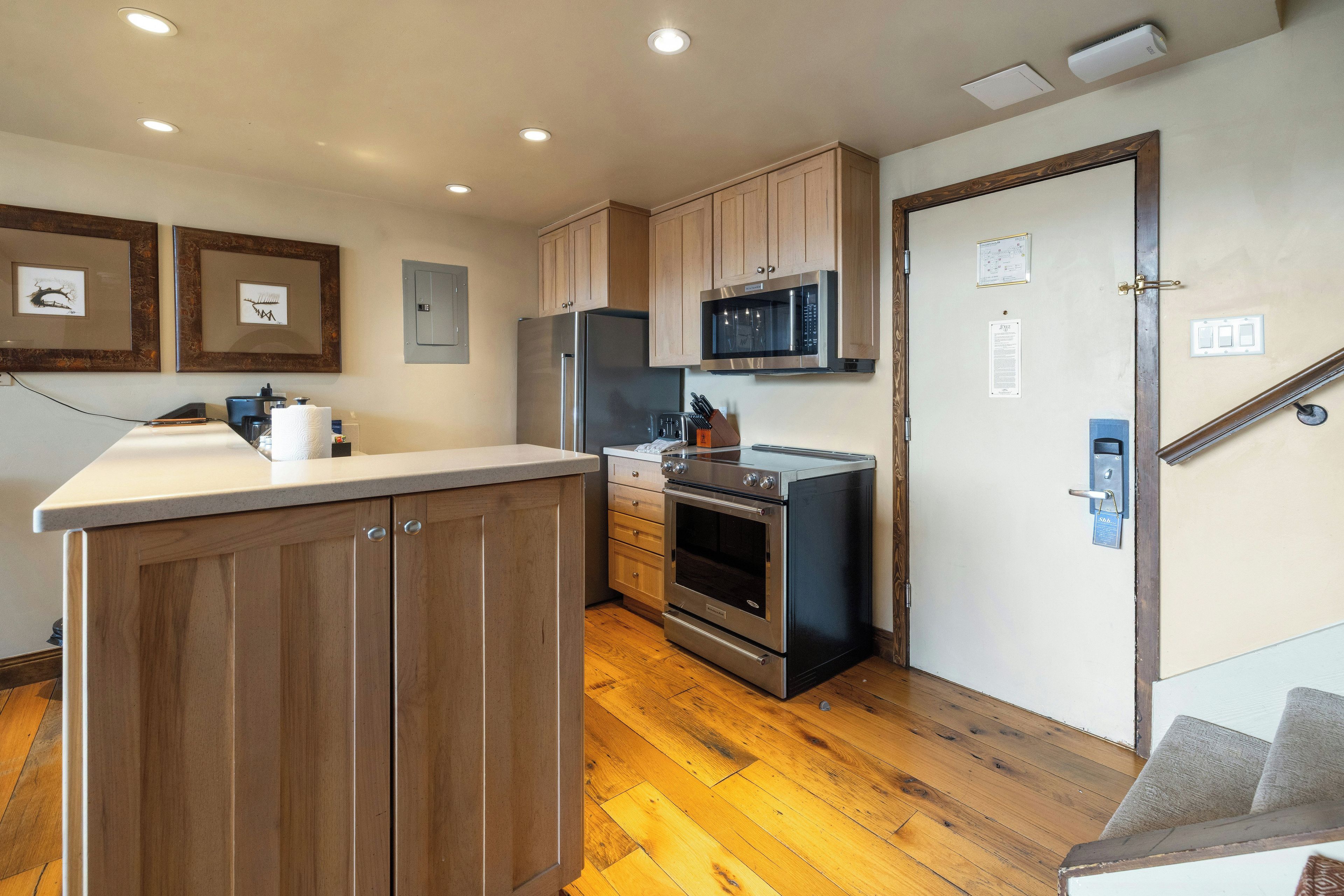 Una cocina moderna con armarios de madera, electrodomésticos de acero inoxidable y piso de madera.