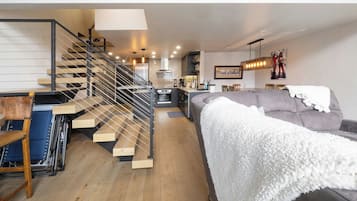 Un interior moderno con una escalera, un sofá y una zona de cocina.