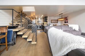Un interior modern amb una escala, un sofà i una cuina.