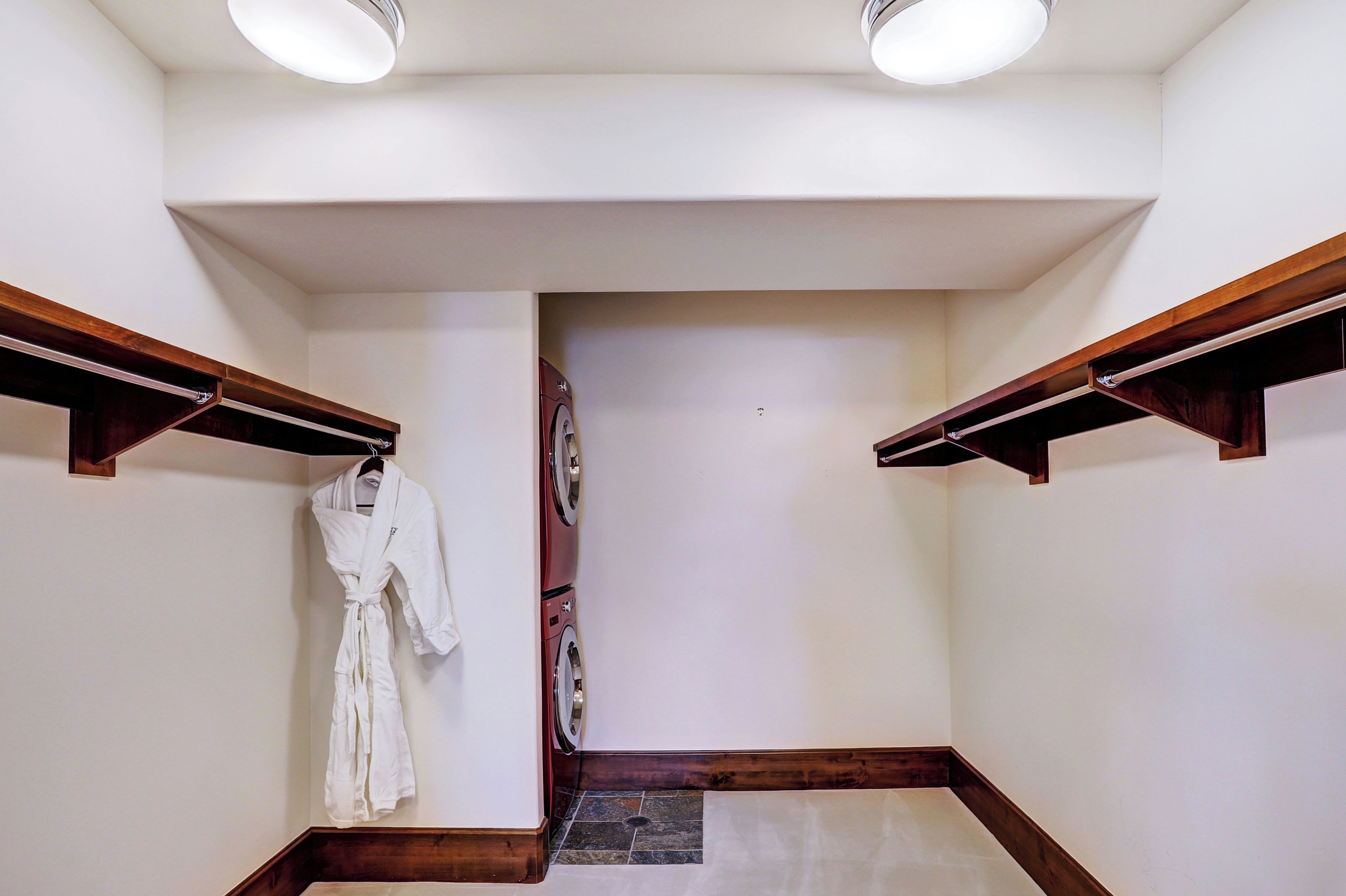 A laundry room with a washing machine, a drying rack, and a white robe hanging on the wall.